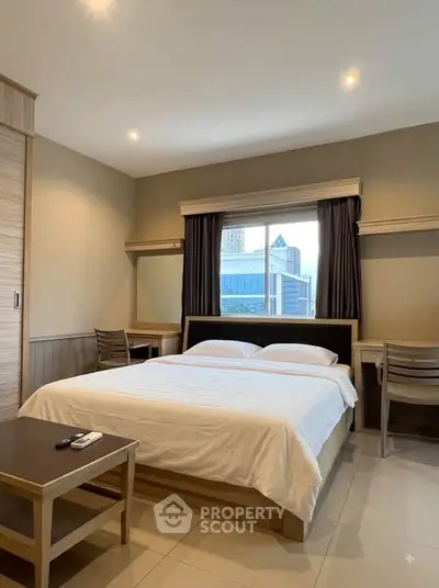 Spacious bedroom with city view, modern furnishings, and ample natural light.