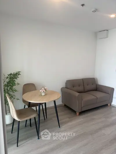 Cozy living room with modern sofa and dining set, perfect for small spaces.