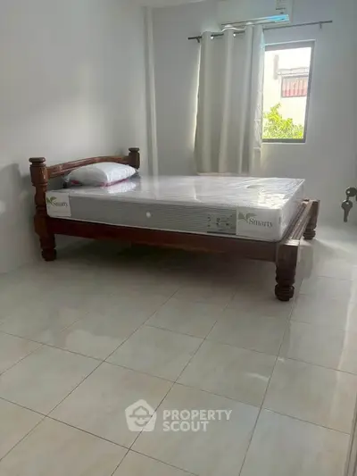Spacious bedroom with wooden bed frame and natural light from window