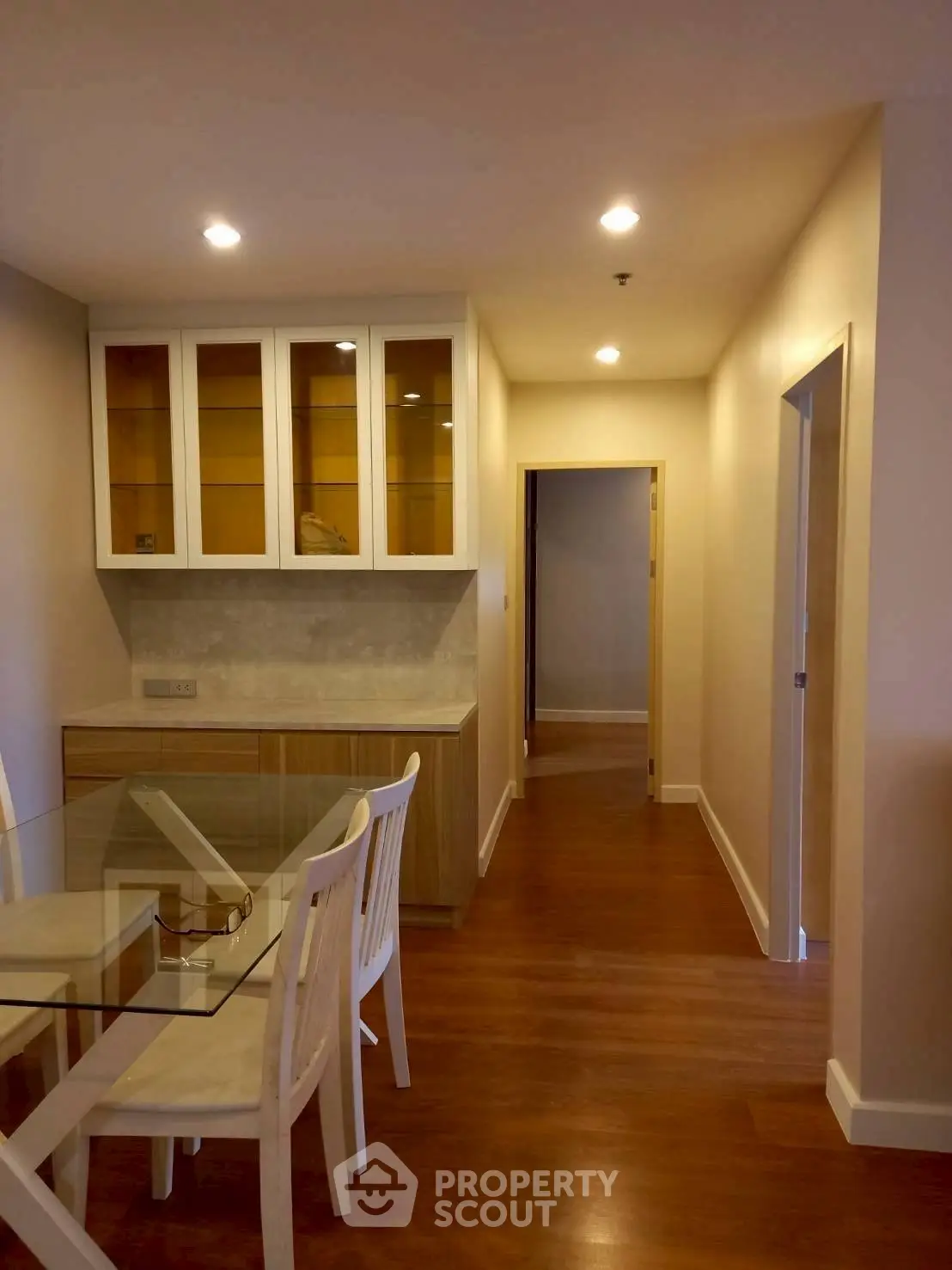 Modern dining area with glass table and wooden flooring in cozy apartment.