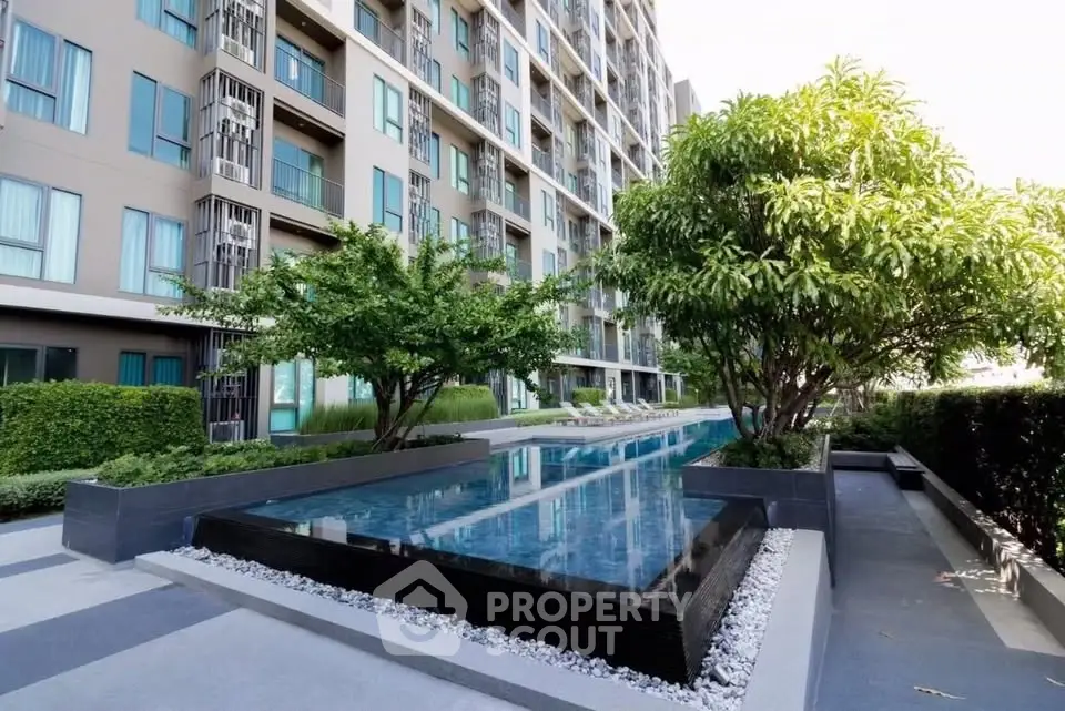 Modern apartment building with sleek pool and lush greenery, offering a serene urban oasis.