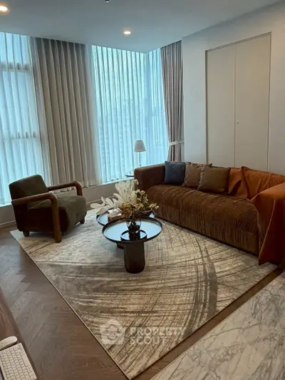 Elegant living room with modern furniture and large windows, featuring a stylish rug and cozy seating area.