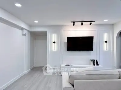 Modern living room with sleek design, featuring a wall-mounted TV and stylish lighting.