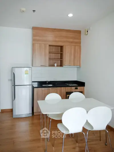 Modern kitchen with dining area, featuring wooden cabinets and sleek appliances.