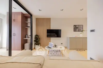 Modern living room with sleek design, featuring a wall-mounted TV, stylish furniture, and a cozy ambiance.