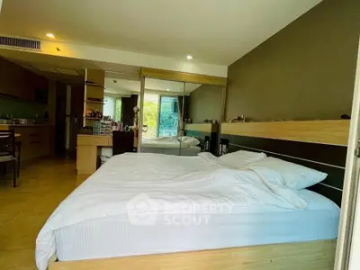 Spacious bedroom with modern decor and large mirror reflecting natural light.