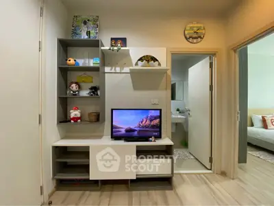 Modern living room with stylish shelving and TV, adjacent to a cozy bedroom and bathroom.