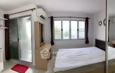 Cozy bedroom with large window and air conditioning, featuring a mirrored wardrobe and minimalist decor.