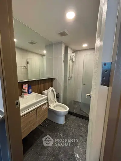 Modern bathroom with glass shower and sleek vanity in contemporary apartment.