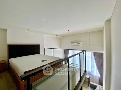 Modern loft bedroom with glass railing and large window view