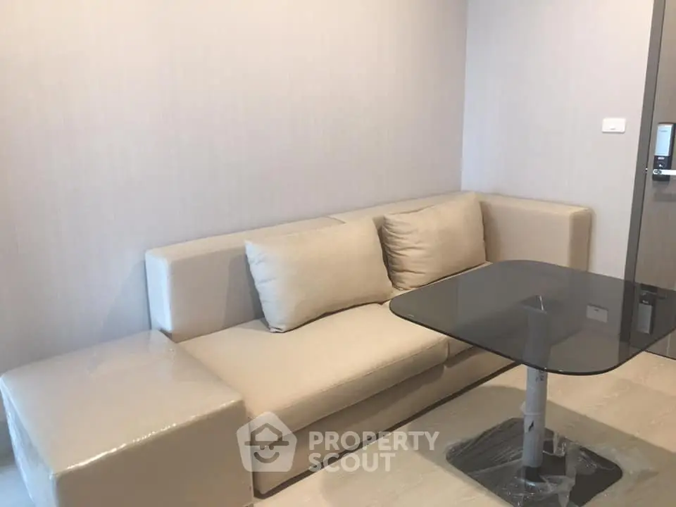 Modern living room with beige sofa and glass coffee table in a stylish apartment.