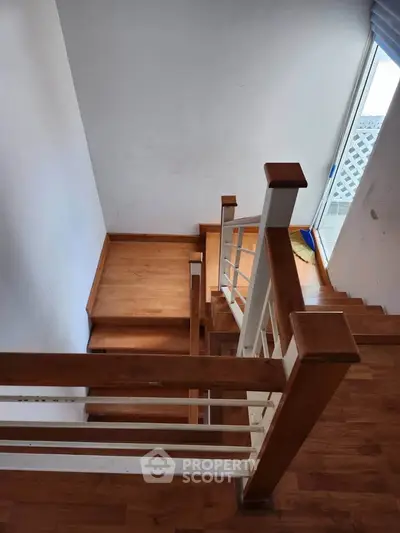 Elegant wooden staircase with natural light and modern railing design