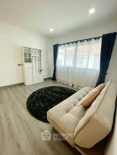 Bright living room with modern decor and large window, featuring a cozy sofa and stylish flooring.