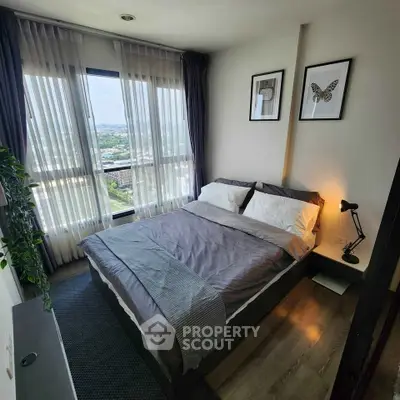 Cozy bedroom with large window and stylish decor, offering a serene view.