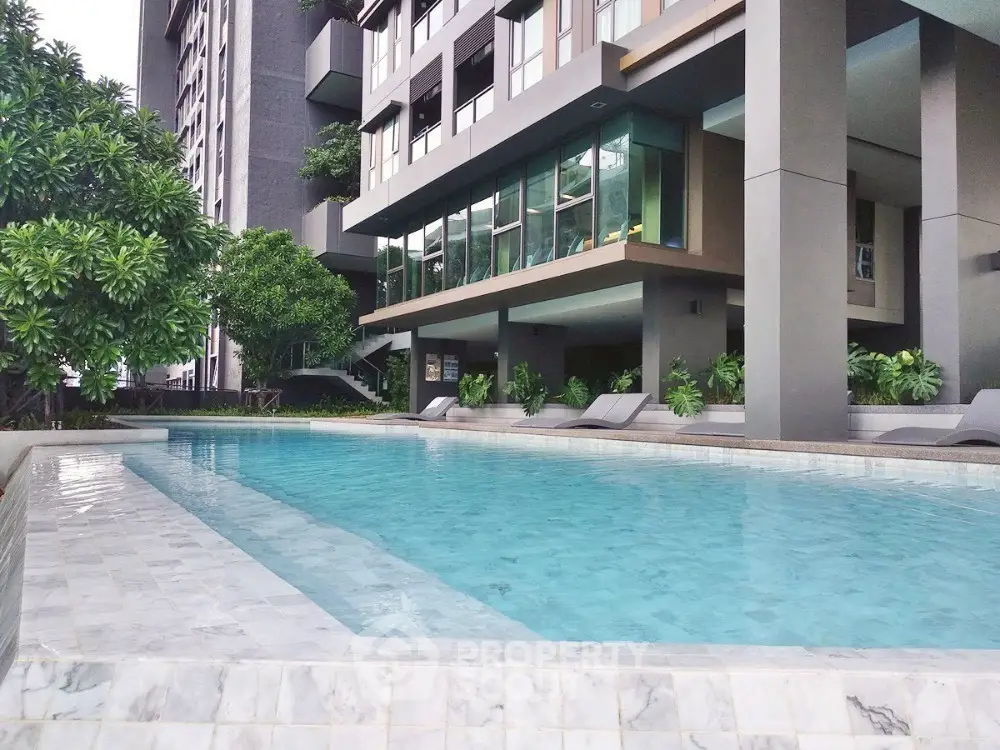 Luxurious modern apartment building with a pristine swimming pool and lush greenery.