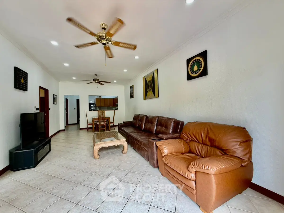 Spacious living room with leather sofas and ceiling fan in modern apartment