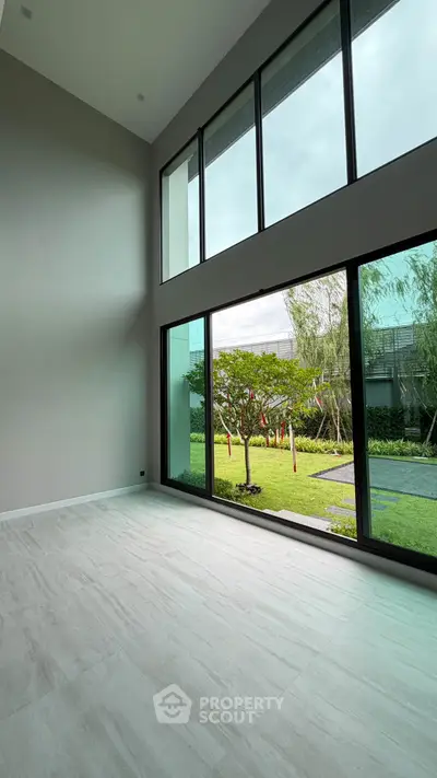 Spacious modern living room with floor-to-ceiling windows and garden view