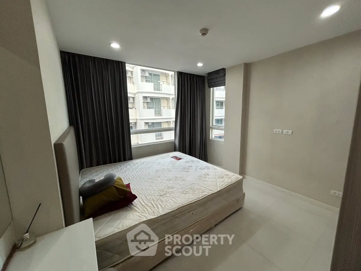 Spacious bedroom with large window and modern decor in urban apartment