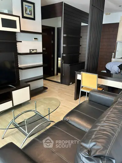 Modern living room with sleek black leather sofa and glass coffee table