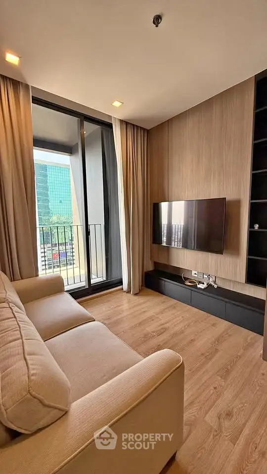 Modern living room with balcony view, featuring sleek TV setup and cozy sofa.