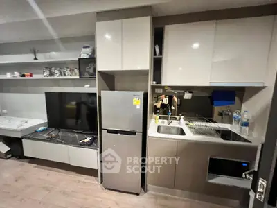 Modern compact kitchen with sleek cabinets and integrated appliances in a stylish apartment.