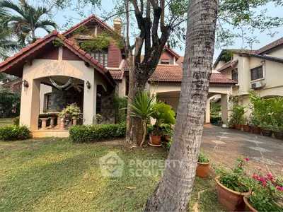 Charming two-story home with terracotta roof tiles, nestled in lush greenery with a well-manicured lawn and inviting entrance, exuding a warm, family-friendly atmosphere.