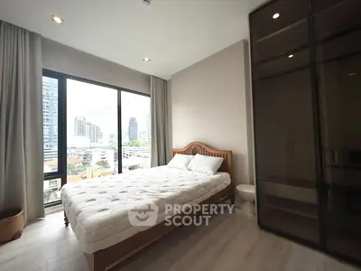 Modern bedroom with city view, large windows, and stylish furnishings in a high-rise apartment.
