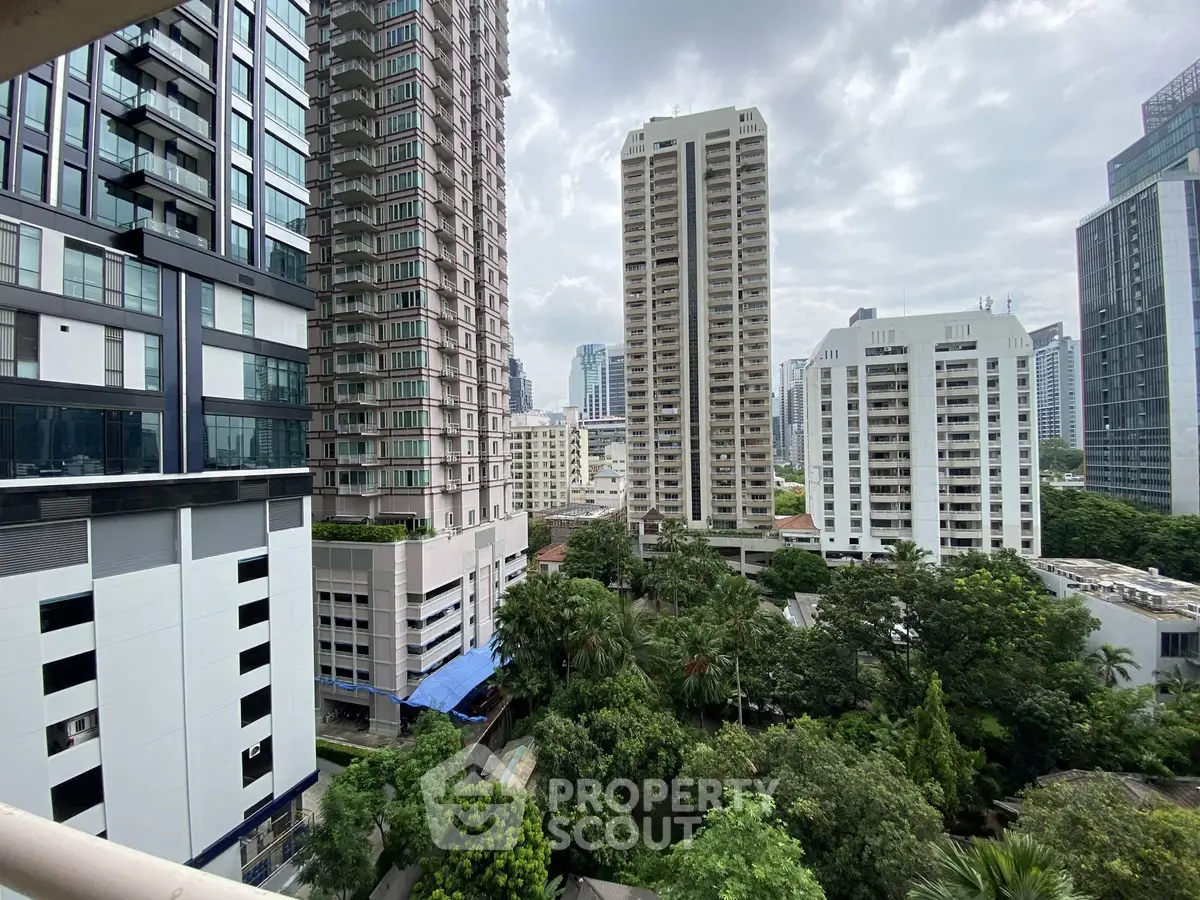 Stunning urban view from a high-rise balcony overlooking lush greenery and modern skyscrapers.