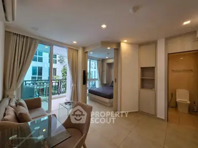 Modern open-plan living room with balcony and bedroom view in luxury apartment.