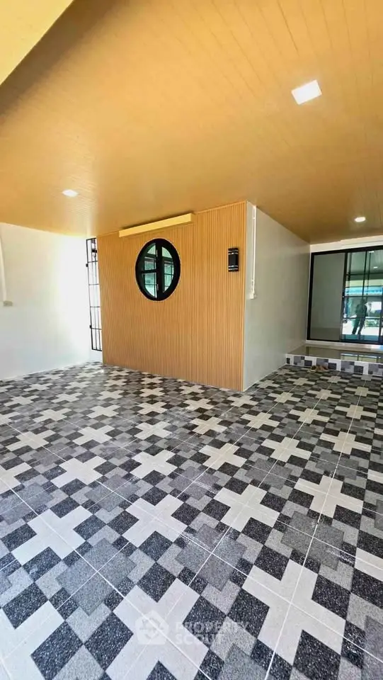 Modern building entrance with stylish tile flooring and unique circular window design.