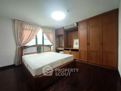 Spacious bedroom with wooden furniture and large window for natural light