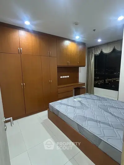 Spacious bedroom with built-in wooden wardrobe and city view window.