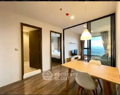 Modern open-plan living and dining area with wooden flooring and city view.