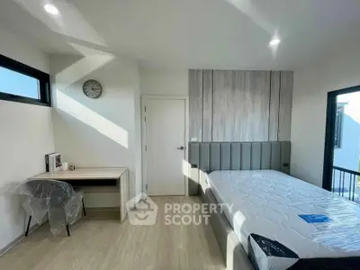Modern bedroom with sleek design and ample natural light, featuring a stylish bed and functional workspace.