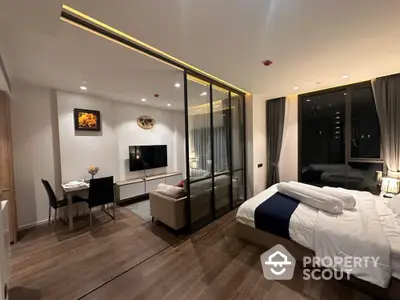 Modern studio apartment with glass partition, cozy living area, and elegant bedroom setup.