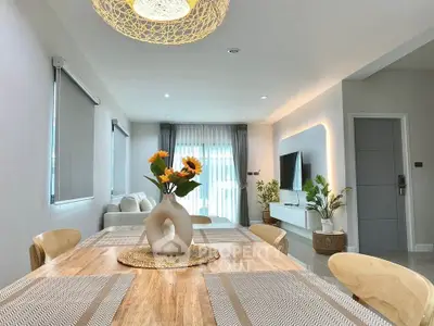 Modern living room with stylish decor and natural light, featuring a dining area and TV setup.