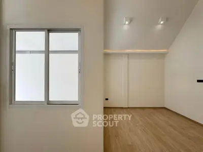 Spacious modern interior with wooden flooring and large window, perfect for customization.