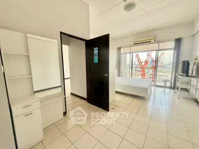 Spacious bedroom with city view and modern furnishings in high-rise apartment.