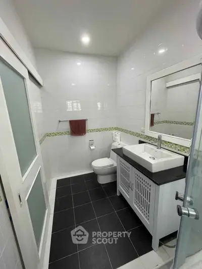 Pristine white-tiled bathroom with modern fixtures, glass shower, and stylish vanity unit, perfect for a refreshing start to the day.