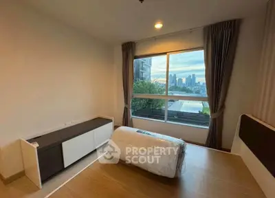 Modern bedroom with city view, large window, and stylish furniture in urban apartment.
