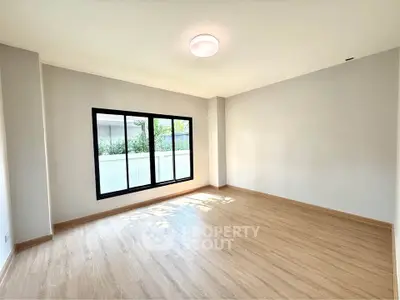 Spacious empty room with large window and wooden flooring, ideal for customization.