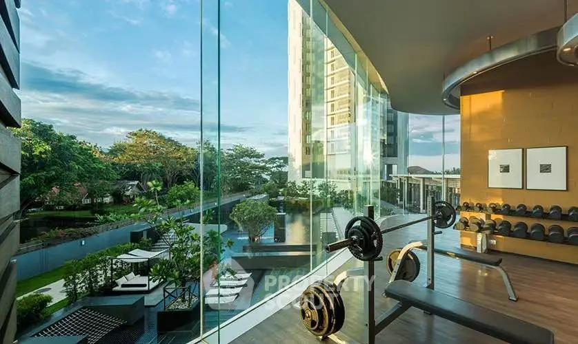 Luxurious gym with panoramic glass walls overlooking a stunning pool and garden view.