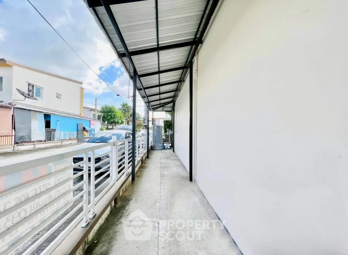 Spacious exterior corridor with modern metal roofing and secure fencing, ideal for urban living.
