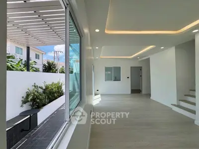 Modern living room with large window and garden view, featuring sleek lighting and open space design.