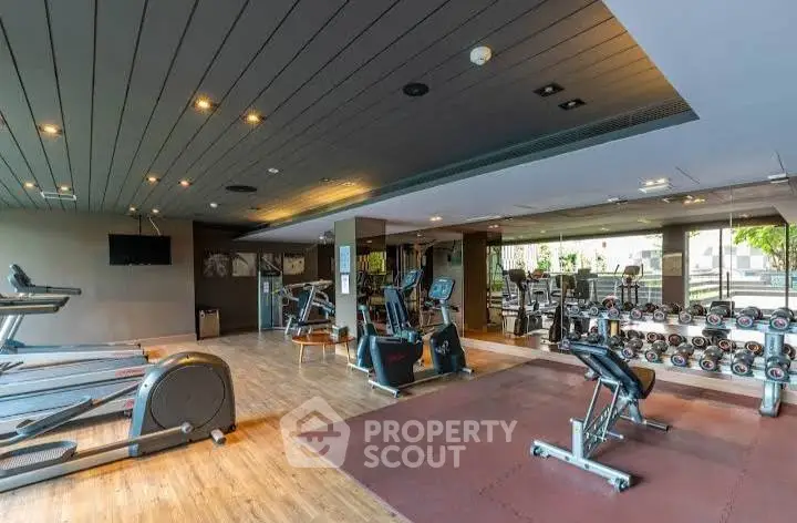 Spacious modern gym with state-of-the-art equipment and wooden flooring.