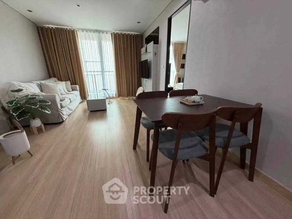 Modern living room with cozy seating and dining area, featuring elegant decor and natural light.