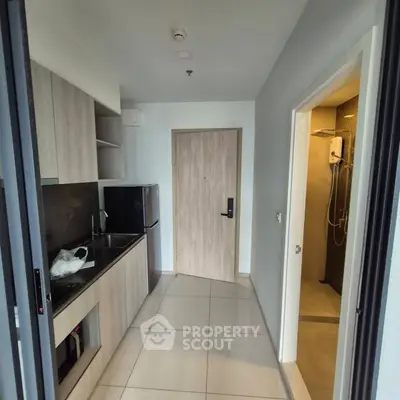 Modern kitchen with sleek cabinetry and adjacent bathroom in a compact apartment layout.