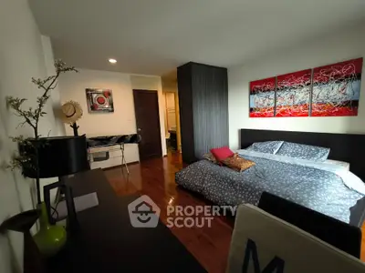 Spacious bedroom with modern decor and wooden flooring in a stylish apartment.