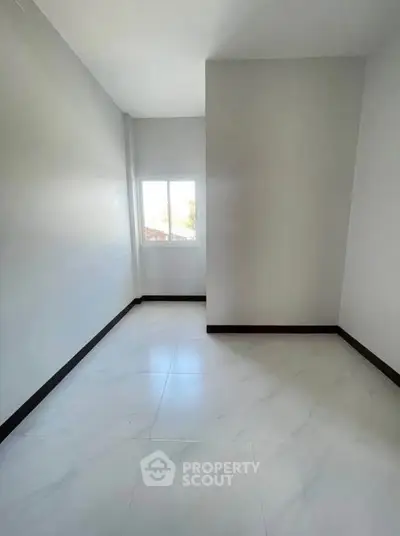 Spacious empty room with large window and tiled floor, perfect for customization.
