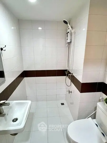 Modern bathroom with sleek white tiles and shower area in a contemporary home.